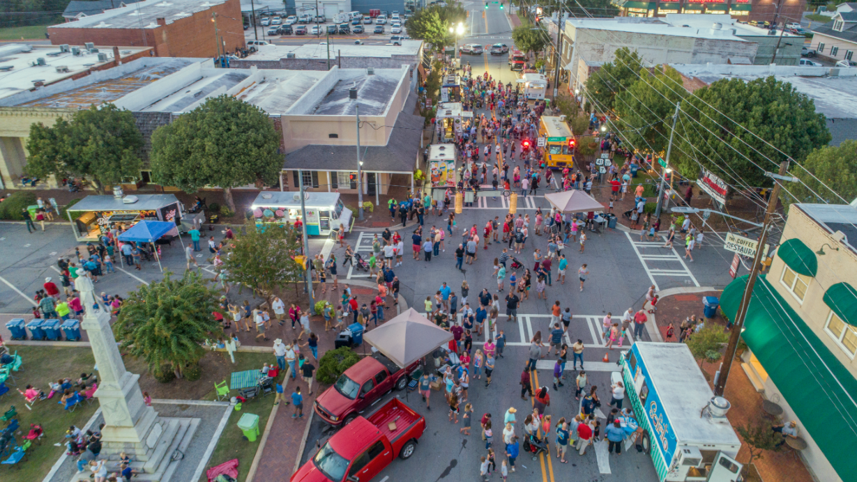 overhead shot of main street during an event, people standi in lines at vendor stations